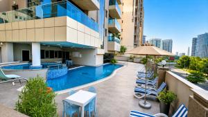 a hotel patio with a swimming pool and chairs at Tulip Creek Hotel Apartments in Dubai