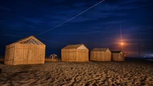 a row of wooden huts on a beach at night at Espace Azaimi in Tarîfa