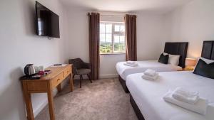 a hotel room with two beds and a desk and a window at Renard Lodge in Cahersiveen