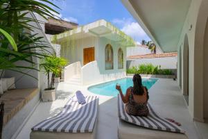 a woman sitting on chairs in front of a swimming pool at The Suite by Ceilao Villas in Ahangama