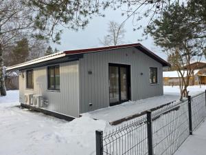 ein kleines Haus im Schnee mit einem Zaun in der Unterkunft Greyhouse in Palanga