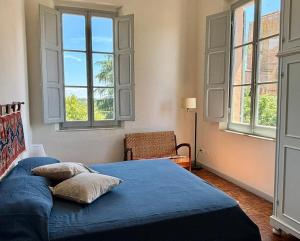 a bedroom with a bed with blue sheets and windows at Le Finestre in Città della Pieve