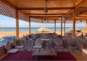 a pavilion at the beach with chairs and a car at Marhaba Camp in Nuweiba