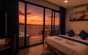 a room with two beds and a balcony with a sunset at The Cliff Bungalow in Koh Rong Sanloem