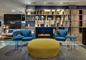 a living room with a yellow ottoman and chairs and a fireplace at Sercotel Ayala in Bilbao