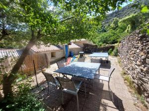 a picnic table and chairs in a yard with a stone wall at Au petit hameau - Votre gîte nature et paisible près du gouffre de Cabrespine in Cabrespine