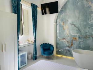 a bathroom with a blue chair and a tub at Zagara Suite in Francofonte