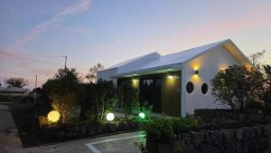 a white house with a stone wall at Jeju Gallery House in Jeju