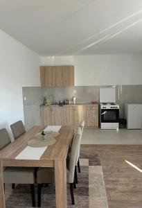 a dining room table with chairs and a kitchen at Apartman Šarenac in Bileća