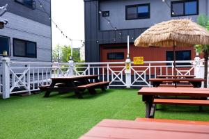 a patio with picnic tables and a straw umbrella at Donghae Gloria Pension in Donghae