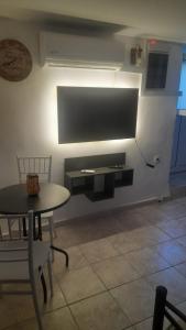 a dining room with a table and chairs and a tv at Arena's nest in Áyioi Dhéka