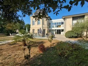 a building with a palm tree in front of it at Green Hôtels Bordeaux Arena in Latresne