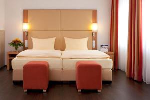 a bedroom with a large bed with two chairs at Welcome Hotel Marburg in Marburg an der Lahn