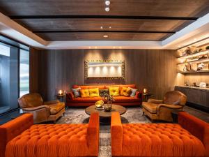 ein Wohnzimmer mit orangefarbenen Sofas, einem Tisch und Stühlen in der Unterkunft CHECK inn SELECT Chiayi RenAi in Chiayi