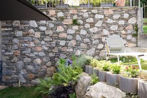 a stone wall with a table and a chair in a garden at Casa Juliette in Bellano +31 photos