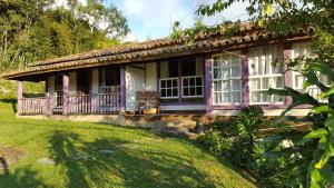 a pink house with a porch and a yard at Pousada Meu Recanto in Conceição da Ibitipoca