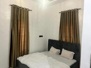 a bed in a room with brown curtains at Universal Apartment & Suites in Ibadan