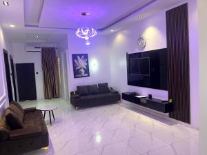 a living room with a couch and a flat screen tv at Universal Apartment & Suites in Ibadan