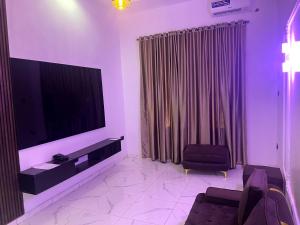 a living room with a large flat screen tv at Universal Apartment & Suites in Ibadan