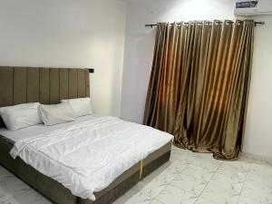 a bedroom with a bed and a window with curtains at Universal Apartment & Suites in Ibadan +11 photos