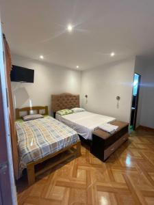 a bedroom with two beds and a tv in it at Hospedaje vista del sur paracas in Paracas