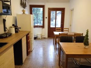 a kitchen and dining room with tables and a refrigerator at Nimród vendégház in Mőcsény