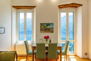 a dining room with a table and chairs and windows at Emy House Charming Apt Stunning Views Balcony AC in Carate Urio