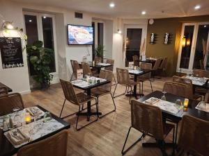 a restaurant with tables and chairs and a tv at Green Hôtels Bordeaux Arena in Latresne