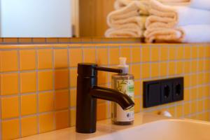 a bathroom sink with a black faucet and a bottle of soap at DAS SILO - Neue Ferienwohnungen und Seminarräume, eröffnet März 2026 in Fröndenberg +78 photos