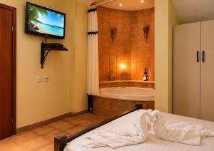 a bathroom with a tub and a bed and a television at נופש דביר - צימרים מהממים למשפחות עם ג'קוזי ובריכה ליד הכנרת in Migdal