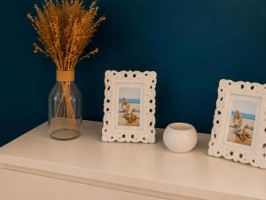 a shelf with two picture frames and a vase with flowers at ROSEVA - T2 Vue mer - Plage à pied - Balcon - Climatisation in Canet-en-Roussillon