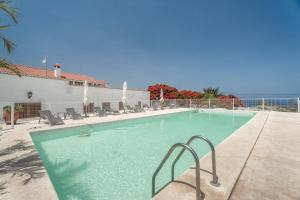 a swimming pool with chairs and the ocean in the background at Finca La Pampa in Arafo