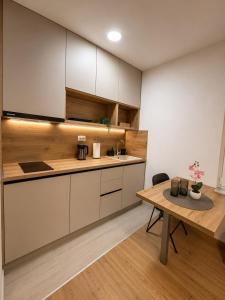 a kitchen with white cabinets and a wooden table at Apartmani Đurišić in Posušje