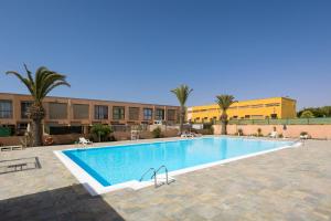 a large swimming pool with palm trees and buildings at CarpeDiem Costa de Antigua in Costa de Antigua