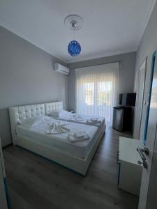 a bedroom with a large white bed and a television at Vila Gregor in Tushemisht
