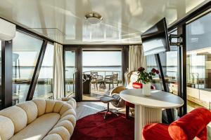 a living room with a couch and a table at HT Houseboats - domki na wodzie - sauna, lake view in Mielno