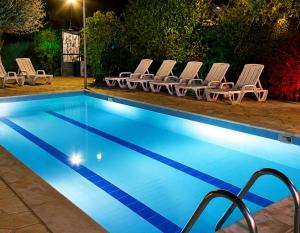 a pool at night with lounge chairs and a swimming pool at נופש דביר - צימרים מהממים למשפחות עם ג'קוזי ובריכה ליד הכנרת in Migdal