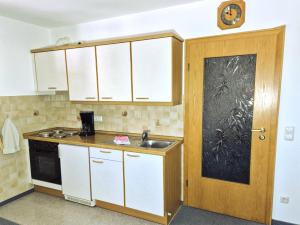 a kitchen with white cabinets and a sink and a door at Ferienwohnung Miesbeck in Burgberg