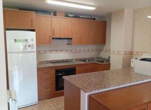 a kitchen with a white refrigerator and wooden cabinets at Pis Relapieso in Vilaller