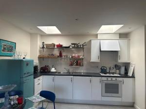 a kitchen with white cabinets and a blue refrigerator at Super comfy, convenient two bedroom apartment in Corsham