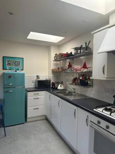 a kitchen with a blue refrigerator and white cabinets at Super comfy, convenient two bedroom apartment in Corsham +5 photos