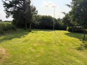 a large grassy yard with trees in the background at Cozy Summerhouse in Vestervig