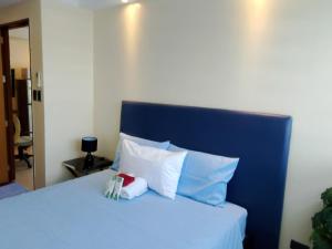 a bed with a blue head board and white pillows at R2 condotel tower in Manila