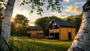 a wooden cabin in the middle of a field with trees at Mazurska Puszcza domek pod klonem z balią ogrodową in Budy