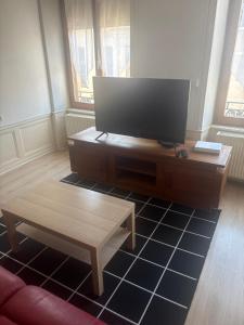 a living room with a flat screen tv and a coffee table at Belle appartement in Saint-Mihiel