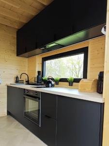 a kitchen with a black stove and a window at Mazurska Puszcza domek pod klonem z balią ogrodową in Budy