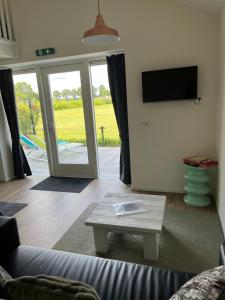 a living room with a couch and a table and a tv at B&B de Landstreek in Hulten