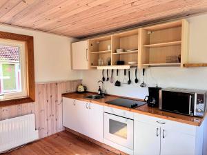 a kitchen with white cabinets and a microwave at Stuga Gösjön in Berga