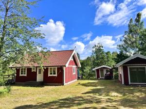 a small red house with a garage in a yard at Stuga Gösjön in Berga