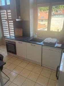 a kitchen with white cabinets and a sink and a window at Belle appartement in Saint-Mihiel